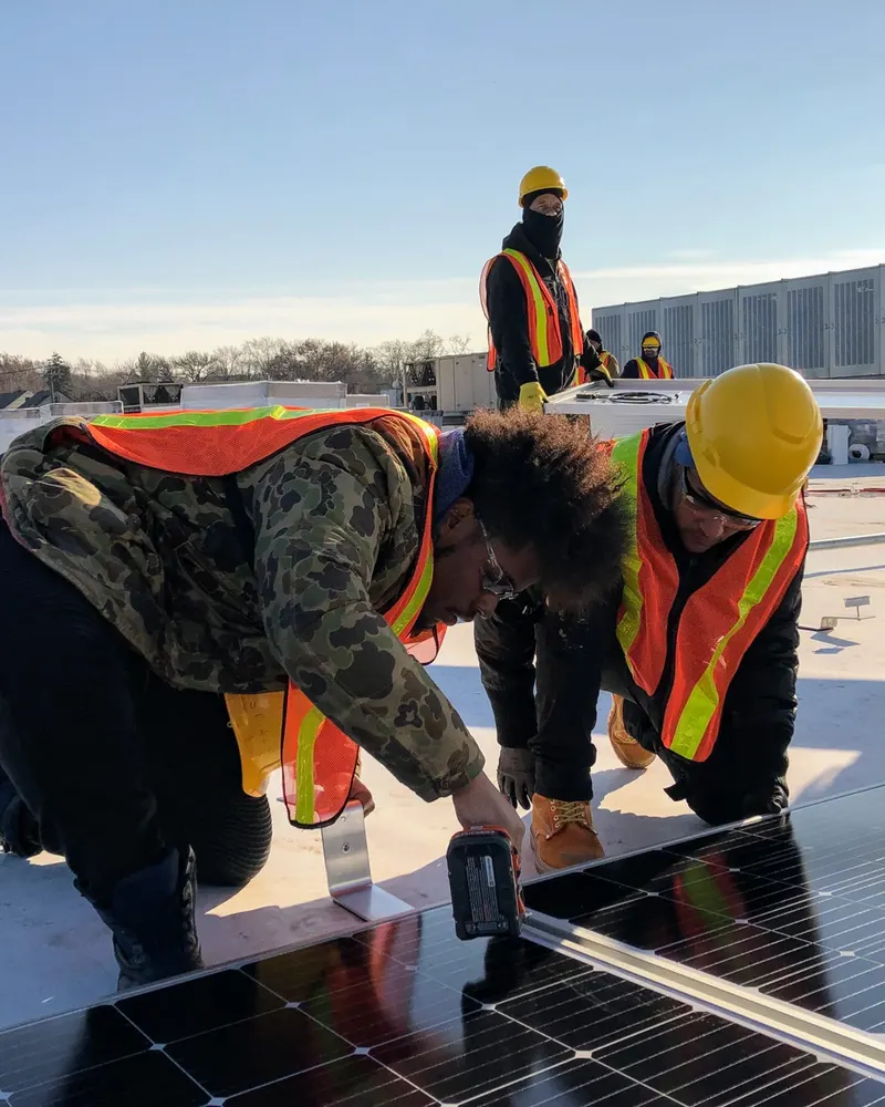 People working together on a solar-panel installation in a supplied photograph from The HOPE Program.